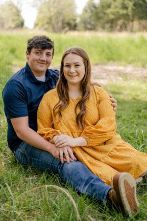 Couple sitting together on grass in casual spring outdoor setting.