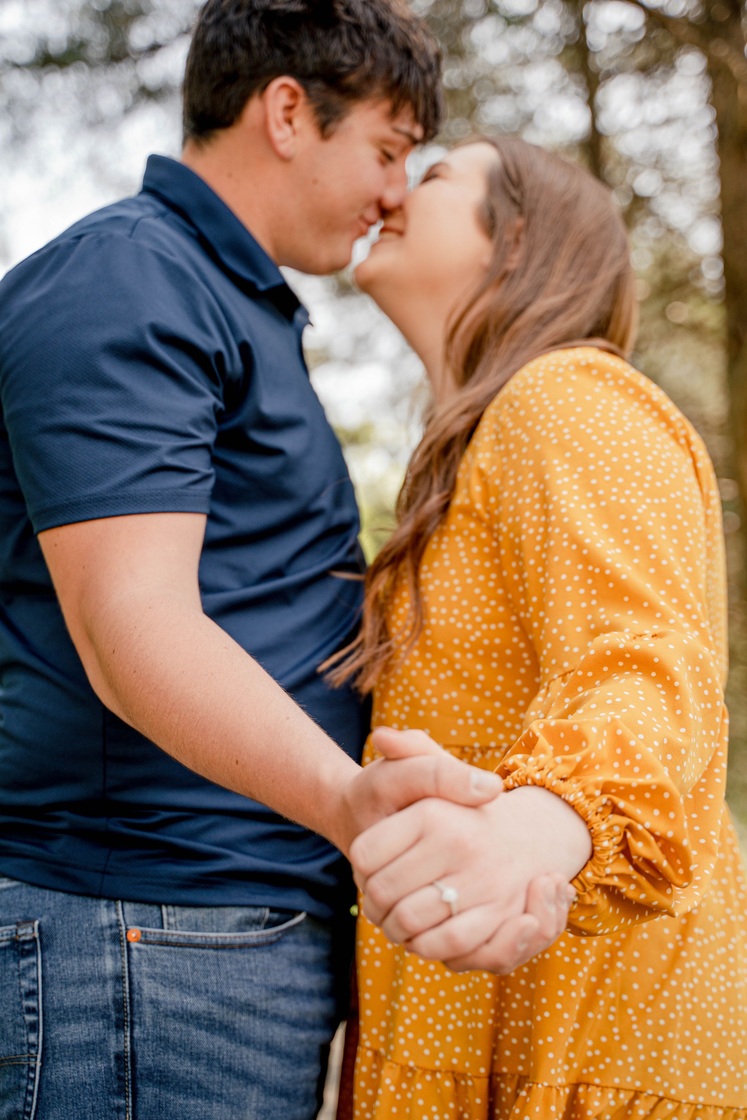 Romantic couple in navy and yellow polka dot outfits sharing an intimate moment outdoors.