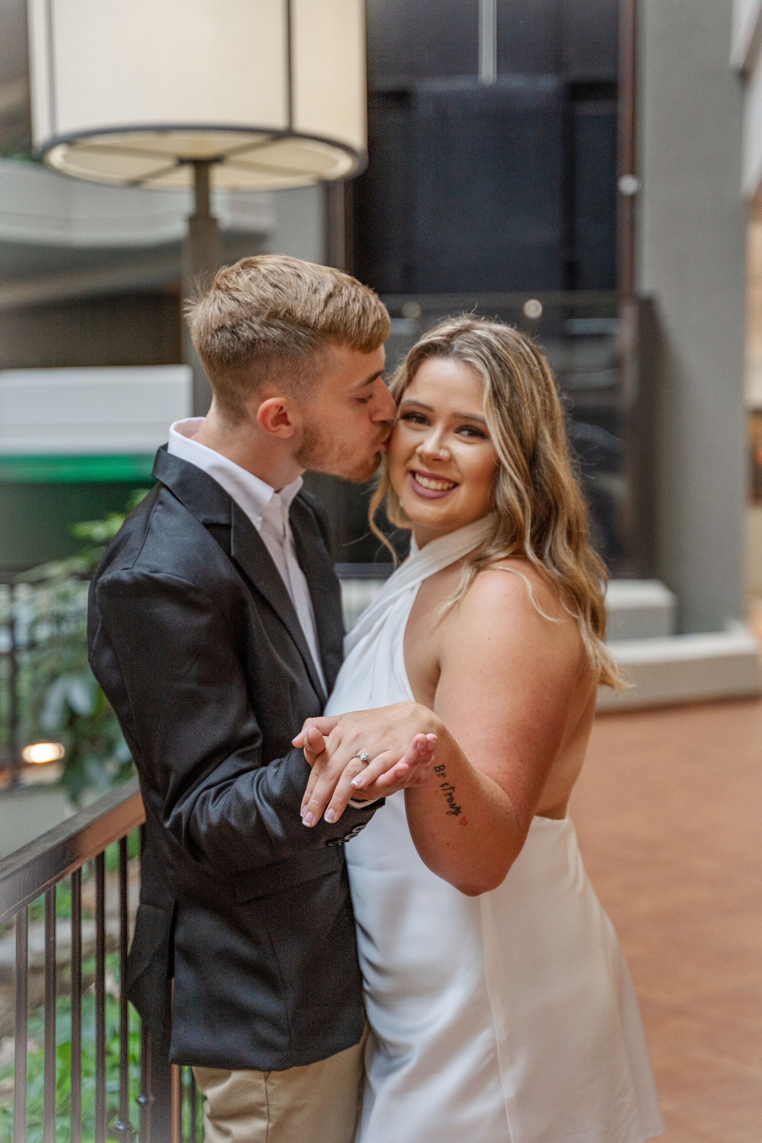 Couple sharing romantic moment on outdoor balcony in formal attire.