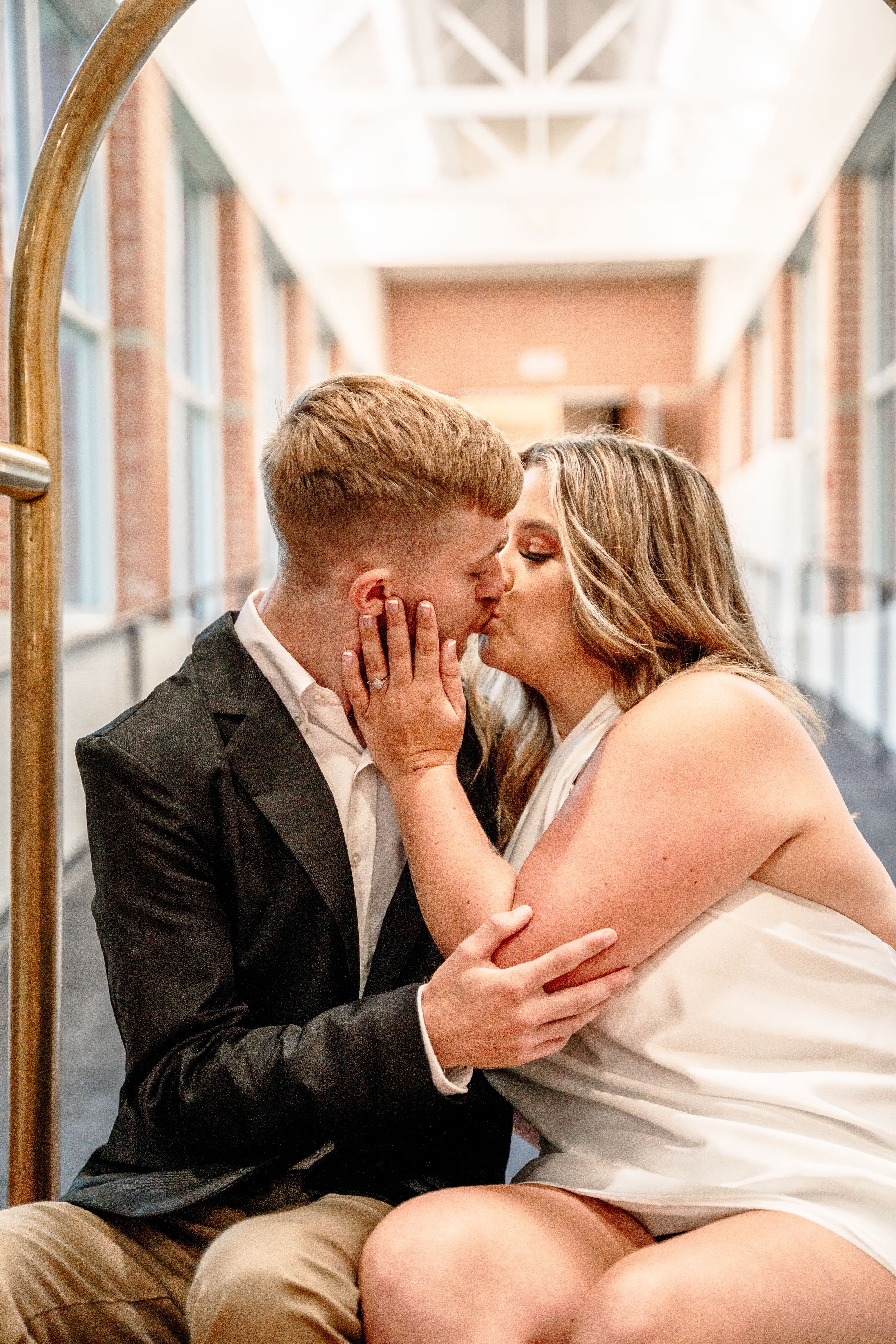 Intimate moment shared between couple on decorative bench in bright corridor.