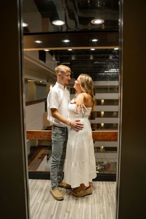 Couple sharing intimate moment in elevator reflection.
