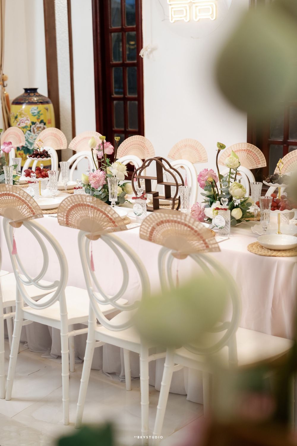 Elegant wedding reception table setup with white chairs and pink floral decorations.