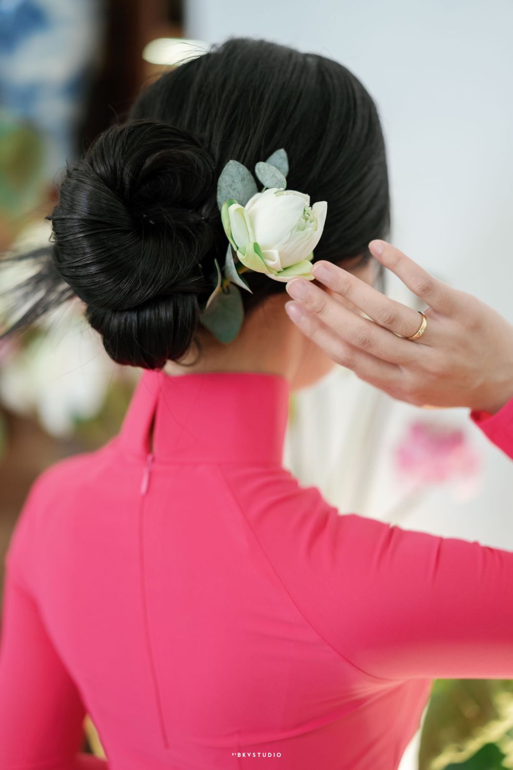 Close-up of an elegant updo hairstyle with white flower accessory and red traditional dress.