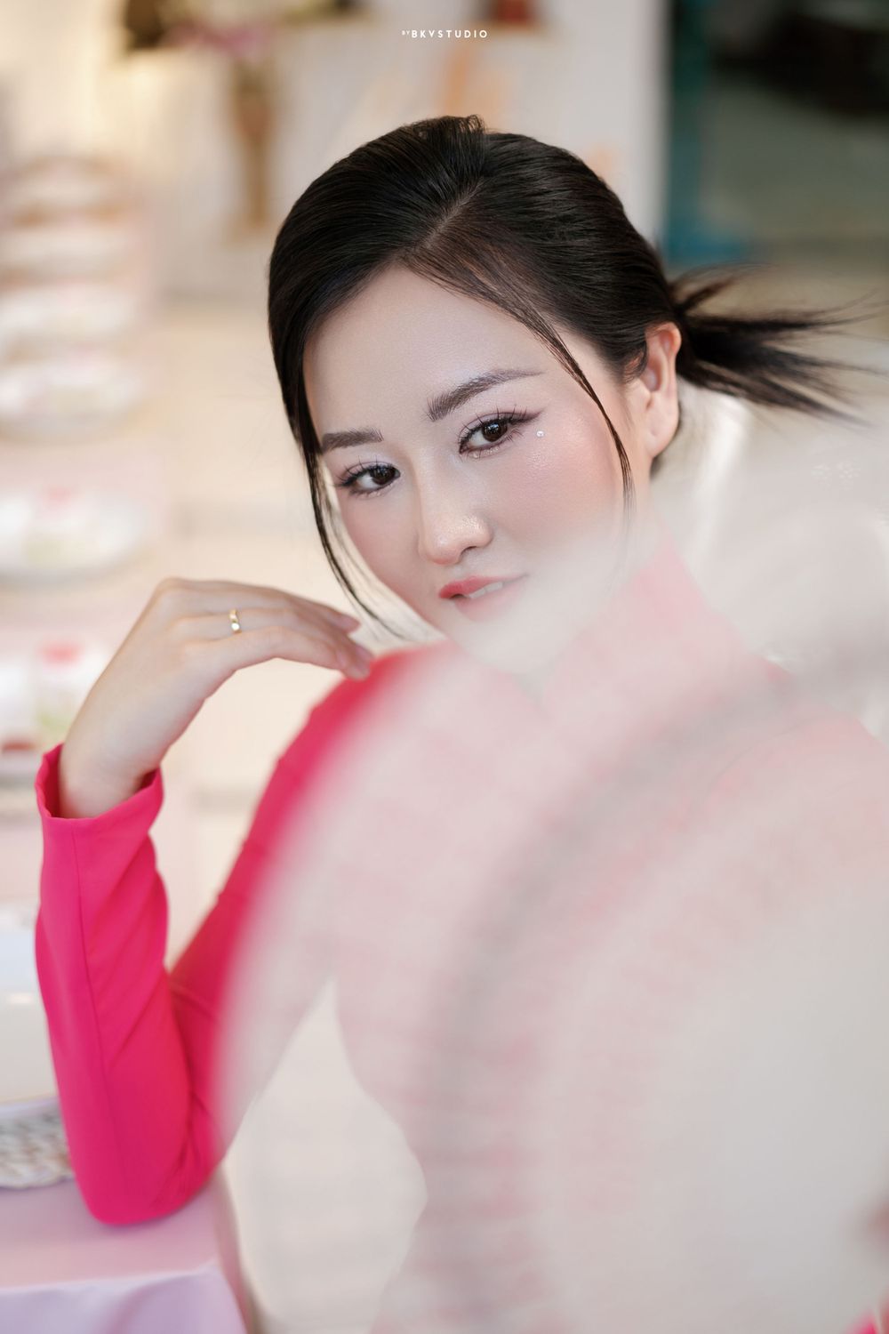 Soft portrait in pink traditional dress against blurred floral background.