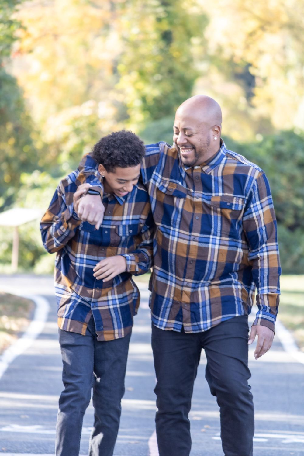 Two people in matching plaid shirts sharing a laugh while walking.