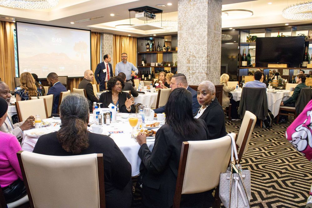 Professionals networking at a formal banquet dinner event in an elegant hotel ballroom with round tables.