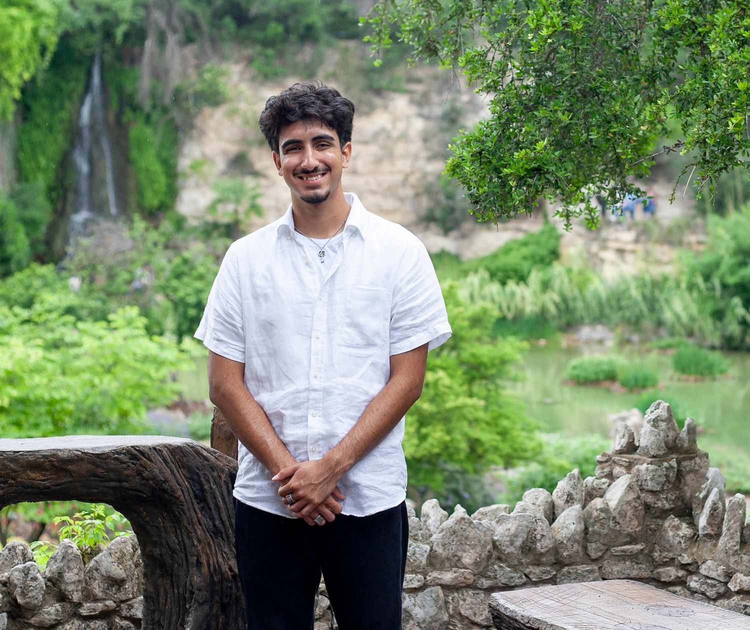 A casual portrait against lush garden scenery with waterfall.