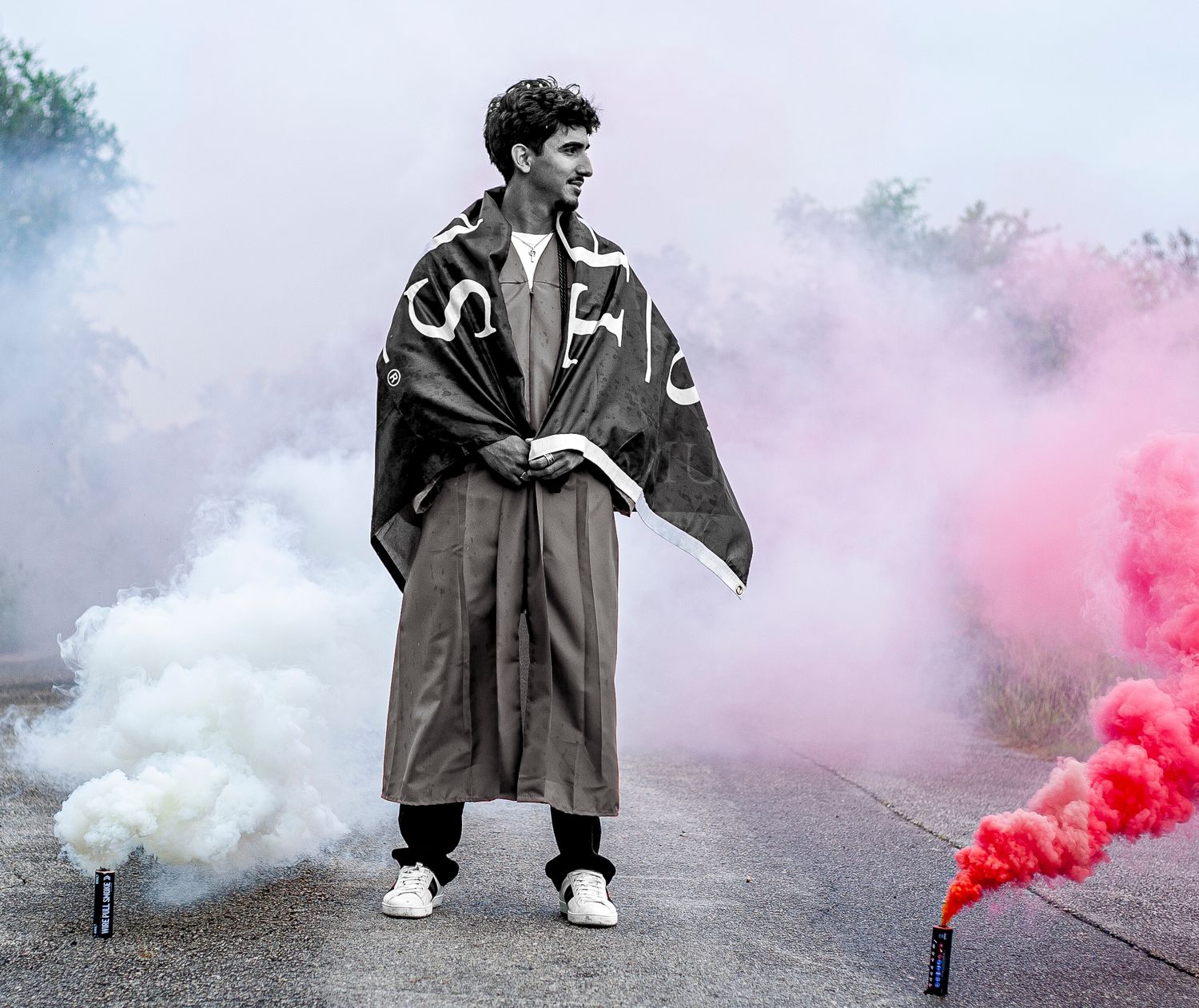 A graduation photo with dramatic red and white smoke effects in black and white.