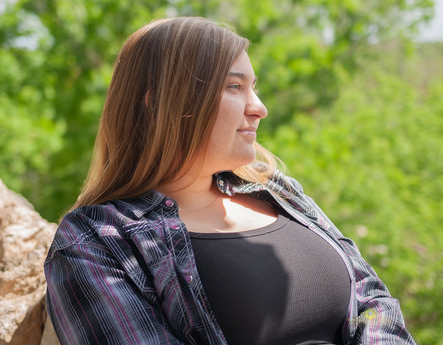 Candid outdoor portrait with natural lighting and stone wall background.