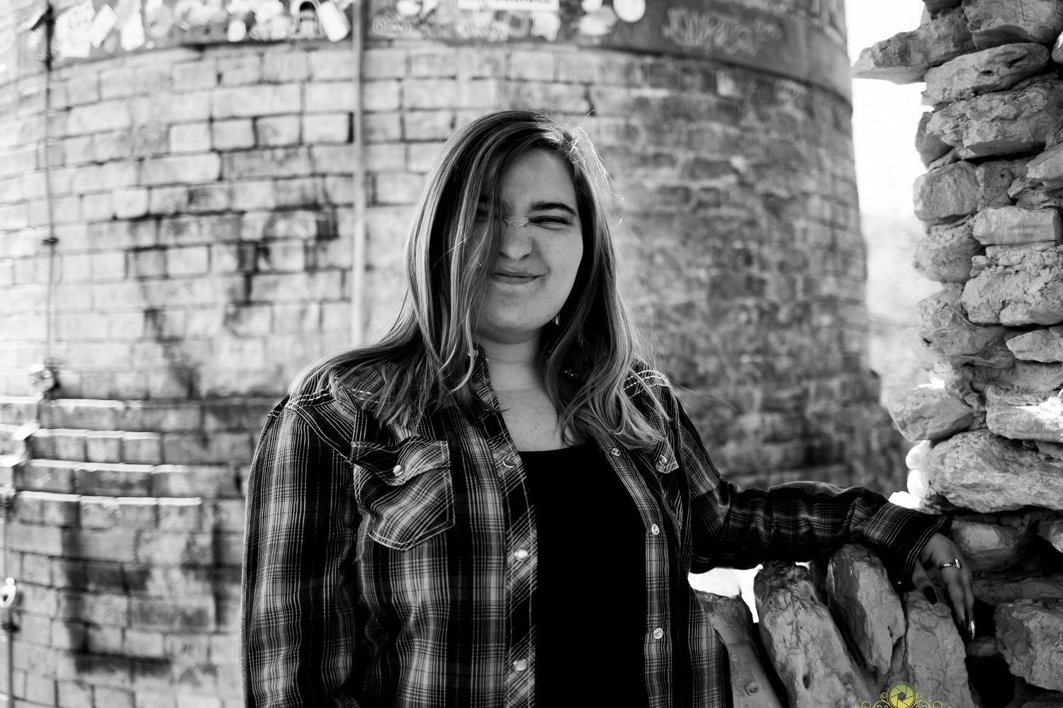 Black and white portrait against brick castle wall and stone archway.