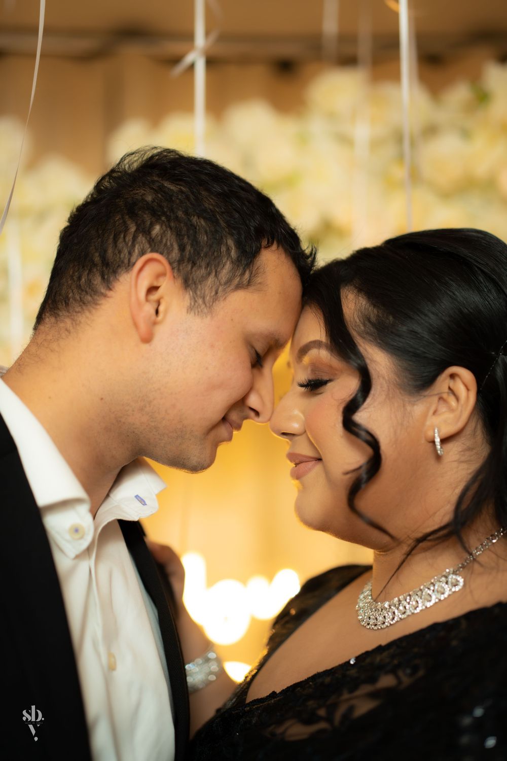 A romantic close-up of a couple in formal wear sharing an intimate moment with soft lighting in the background.
