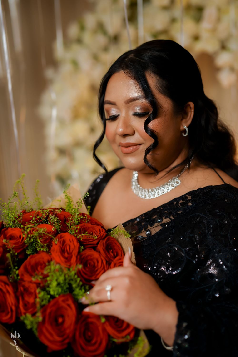 A glamorous figure in a black sequin dress poses with vibrant red roses and delicate jewelry in an elegant portrait series.