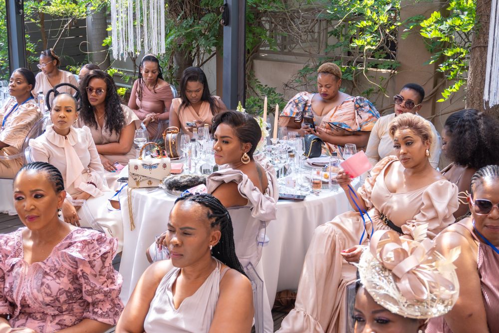 Elegant outdoor dining setup with guests seated at white-clothed tables.