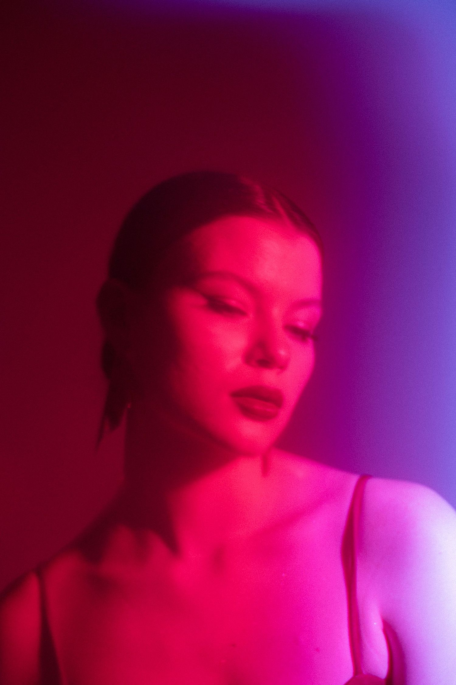 Ethereal portrait bathed in red and purple lighting creating a dreamy atmosphere.