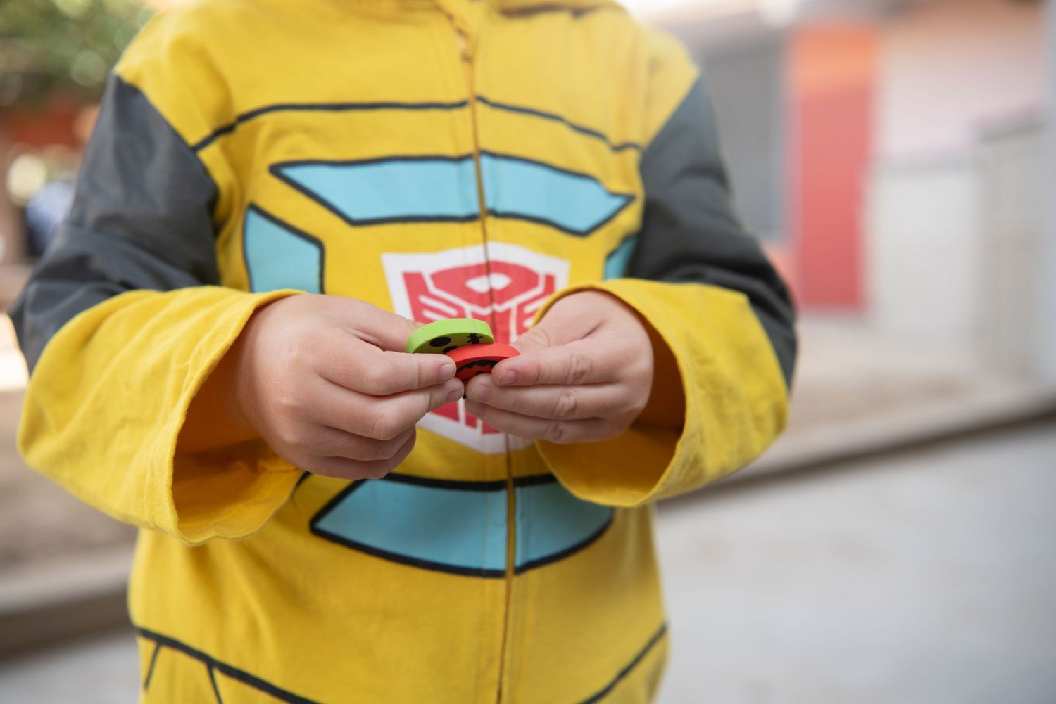 Close-up view of a kid's hands holding green and red Halloween pumpkins on a Halloween party in a nursery school