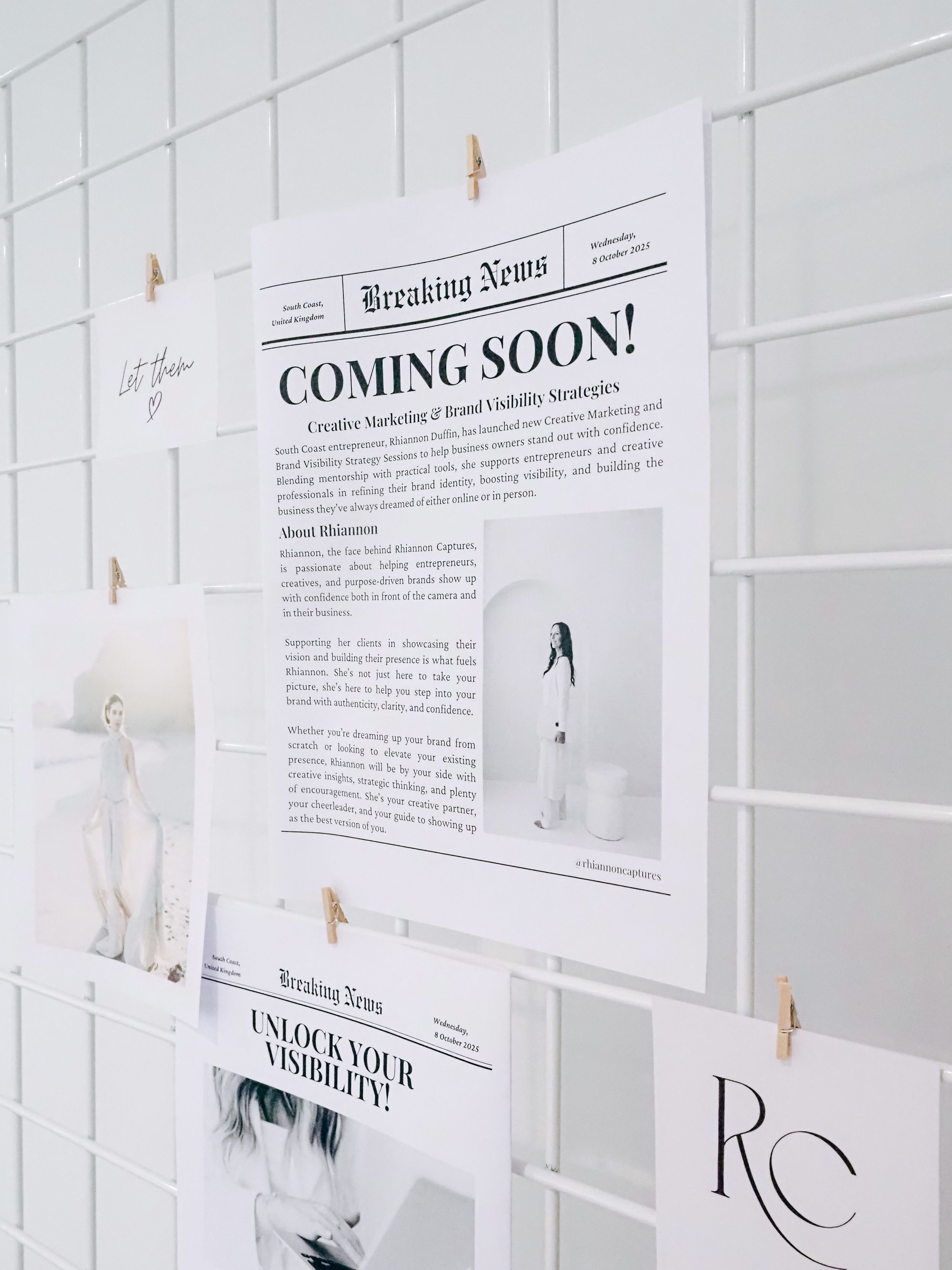 Several white papers with 'Coming Soon' text and design layouts pinned to a white wall with small clips.