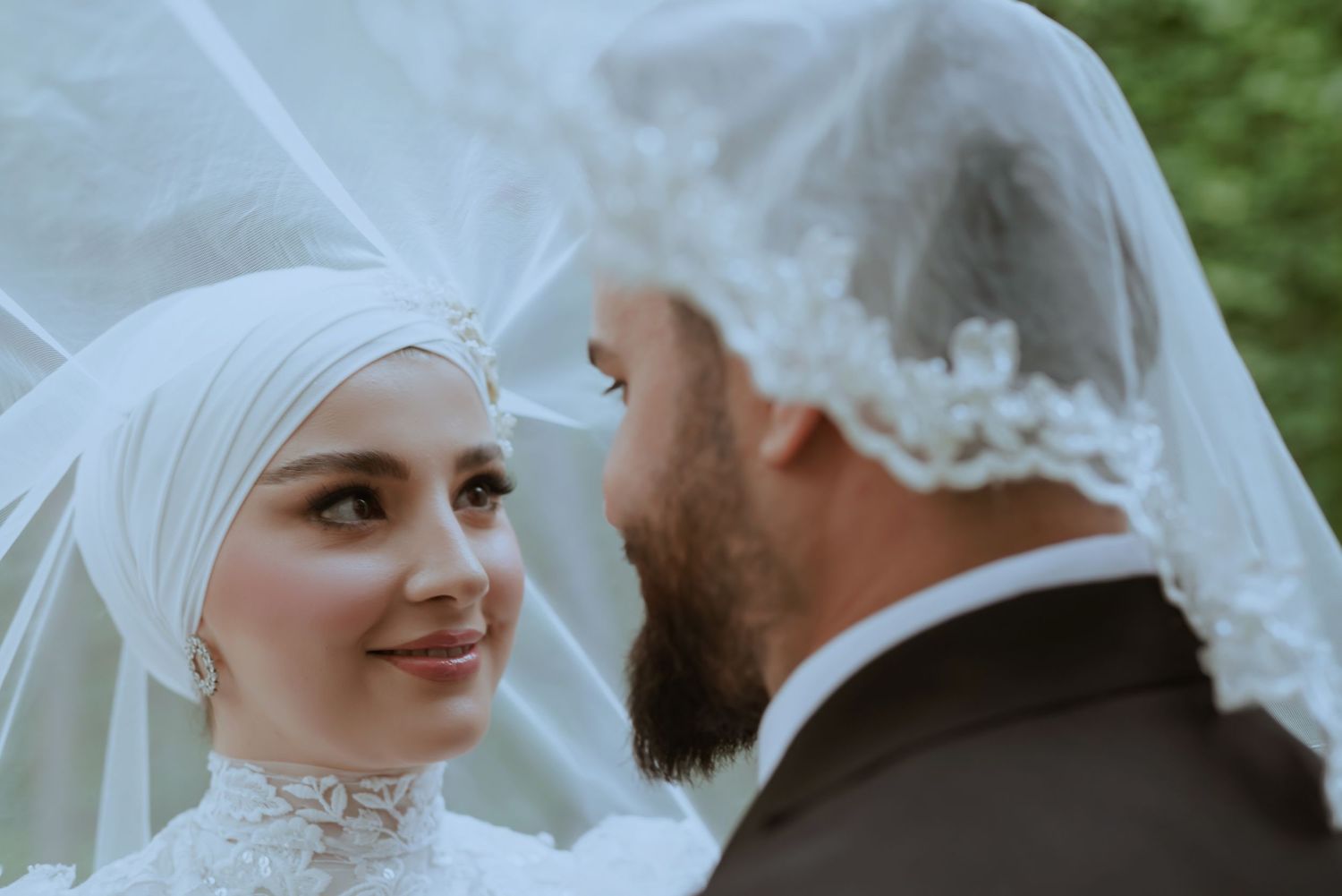 A lovely wedding moment between newlyweds in formal attire with a flowing white veil.