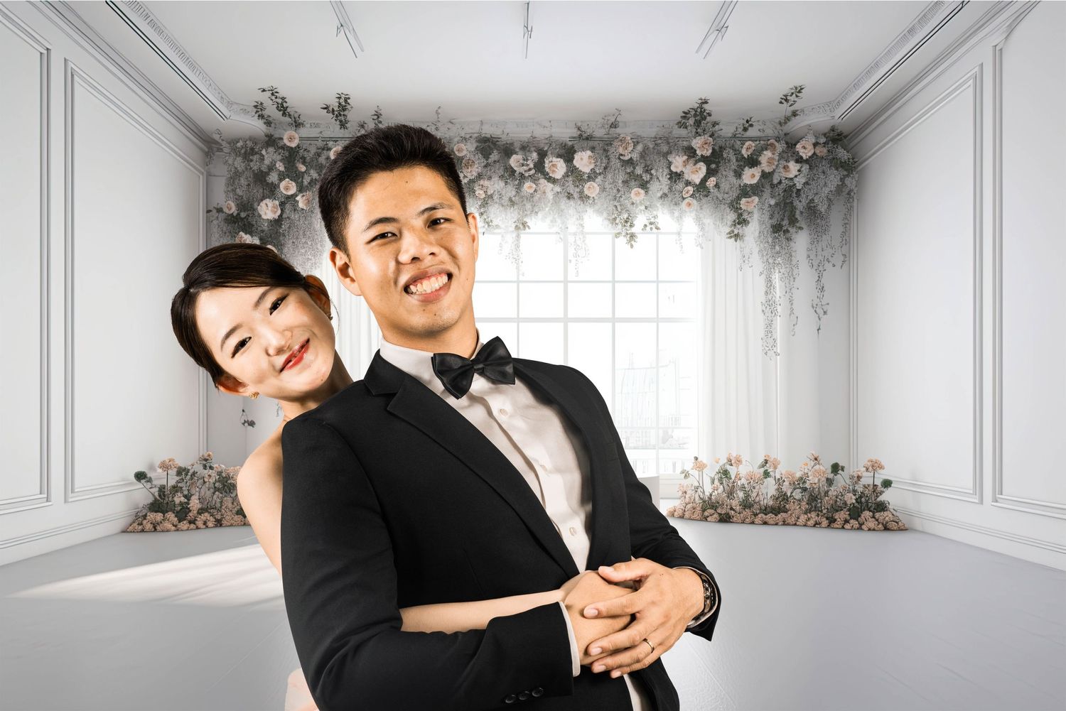 Couple embraces in formal wear against an elegant white room with floral arch decor.