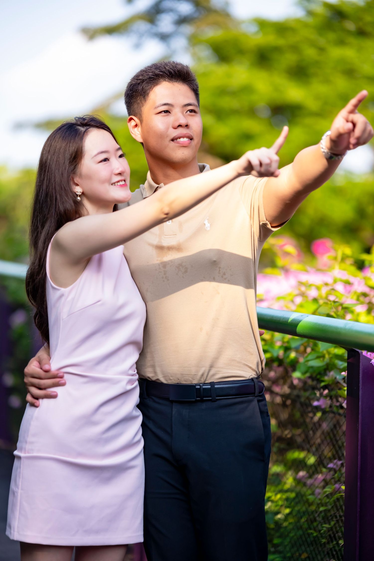 Couple in coordinated outfits pointing at something in garden setting.