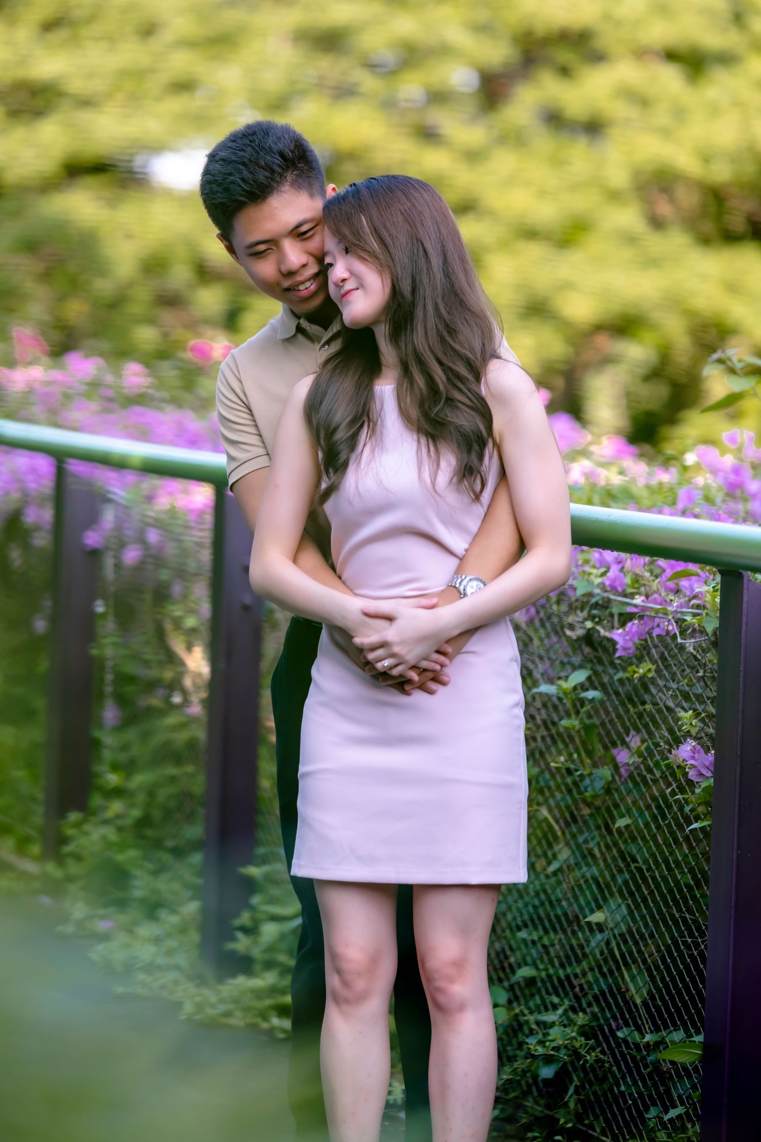 Couple sharing intimate moment by floral garden fence in summer setting.