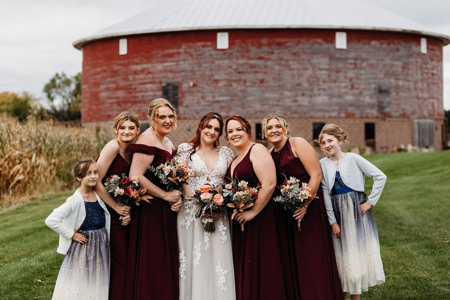 bridesmaids surrounding bride in front of round barn