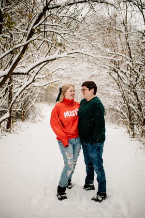 Couple smiling at each other on a snowy forest path