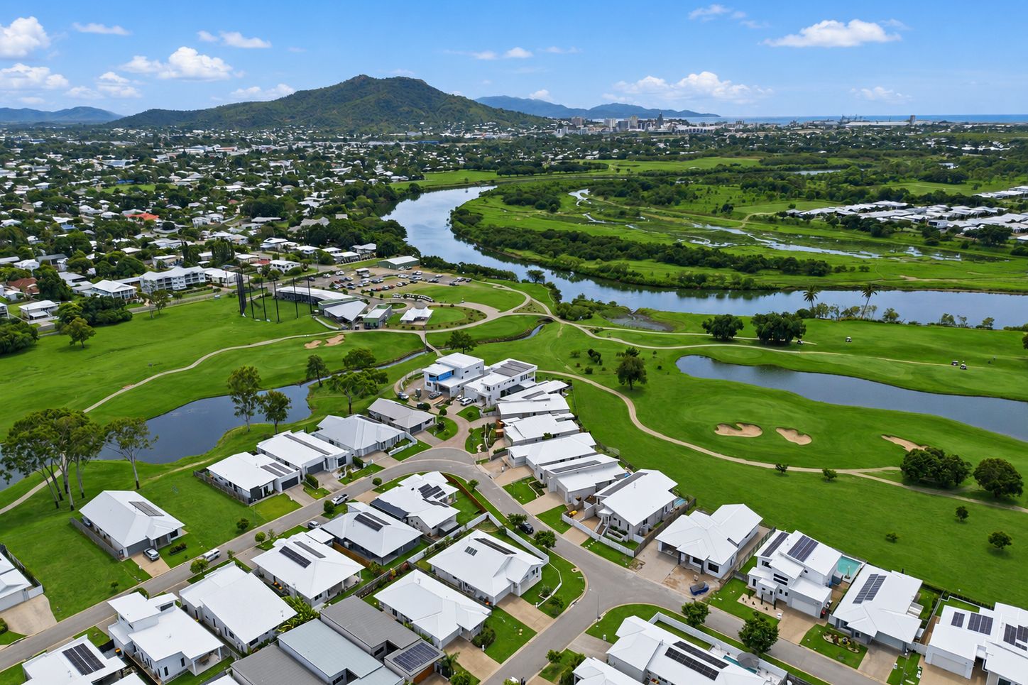 Aerial panoramic view of residential neighborhoods and mountains in a tropical coastal setting.