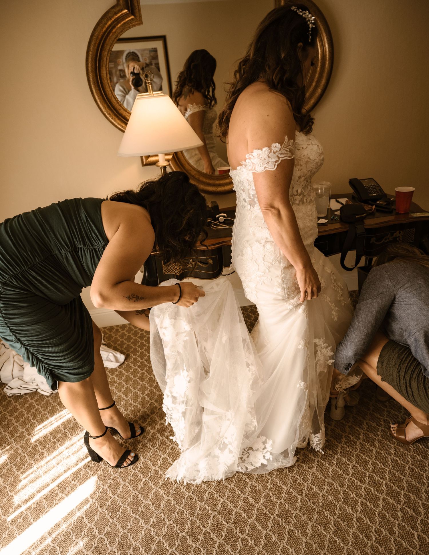 Wedding dress preparations and final adjustments on patterned carpet.