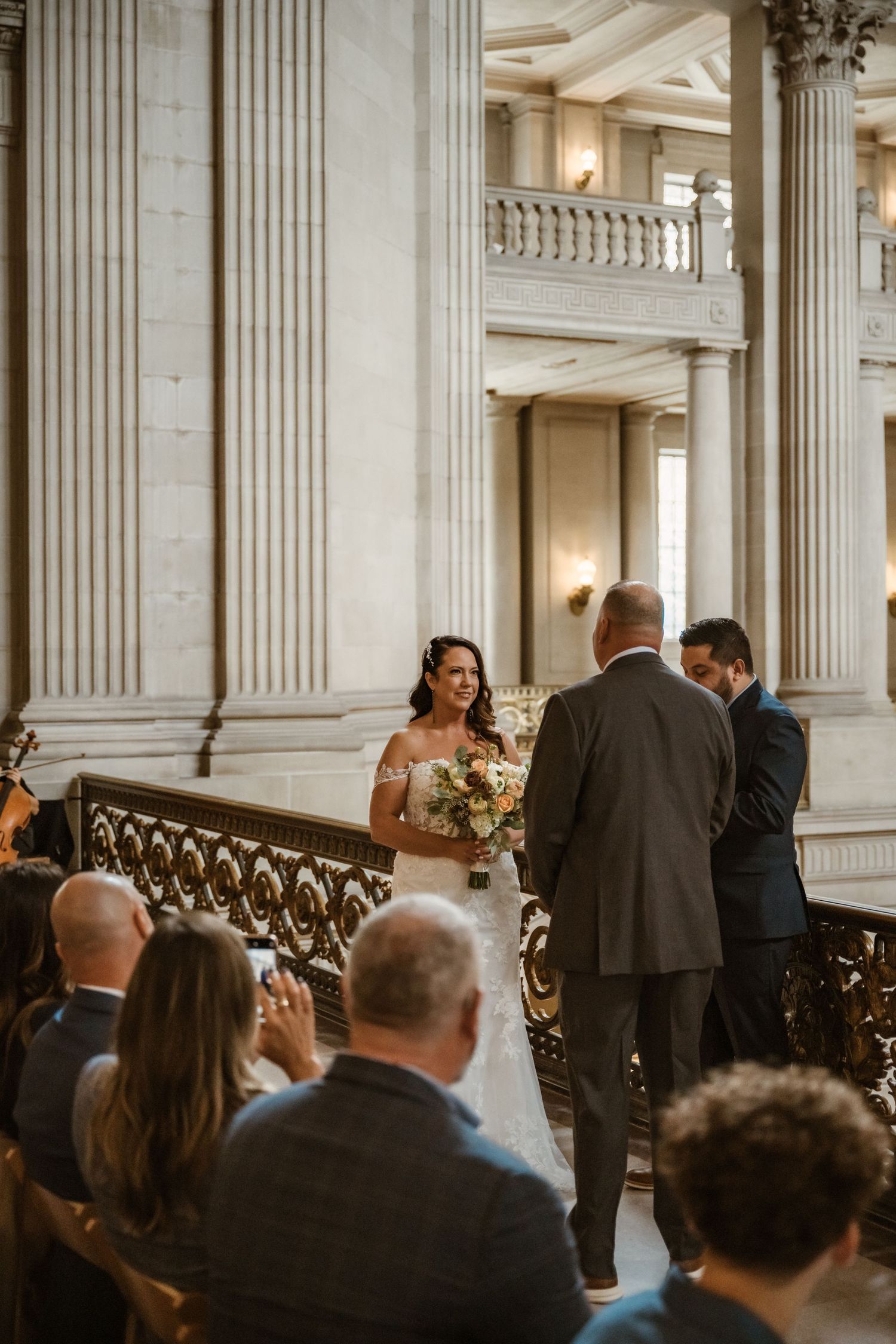 Wedding ceremony in progress inside a historic building with classical columns and elegant architectural details.