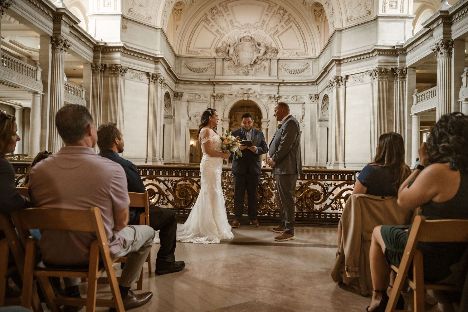 Panoramic view of a wedding ceremony in a historic venue with ornate dome and classical architecture.