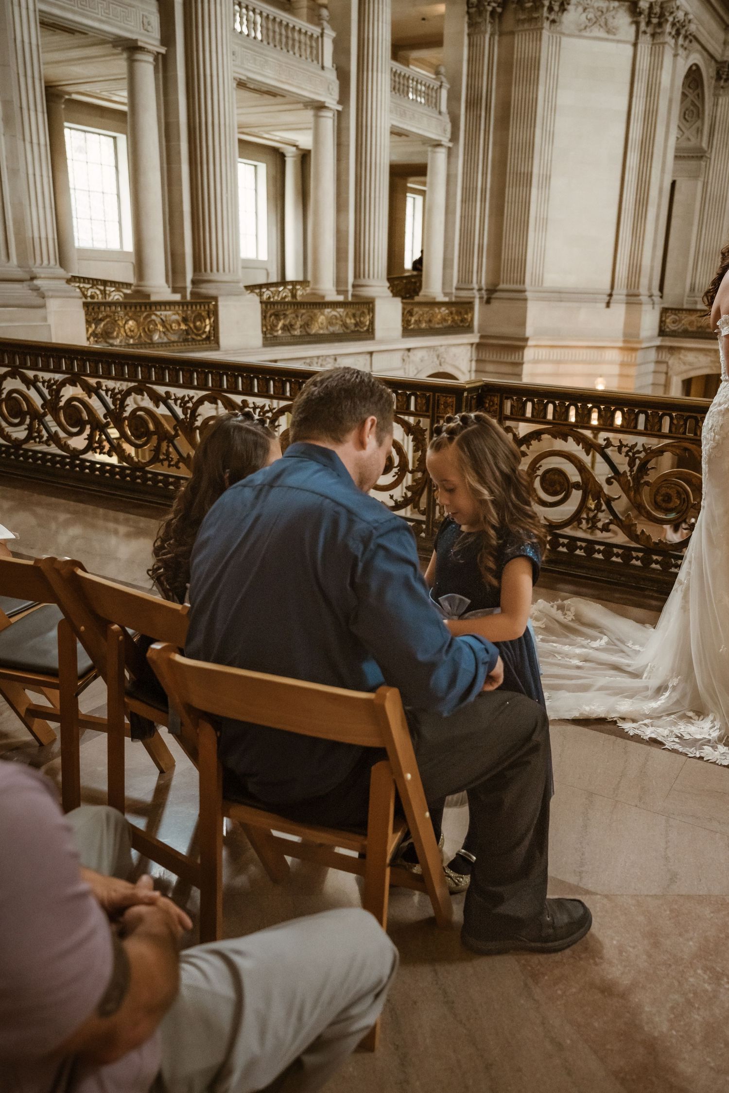 Wedding guests seated in ornate church pews during ceremony in historic building interior.