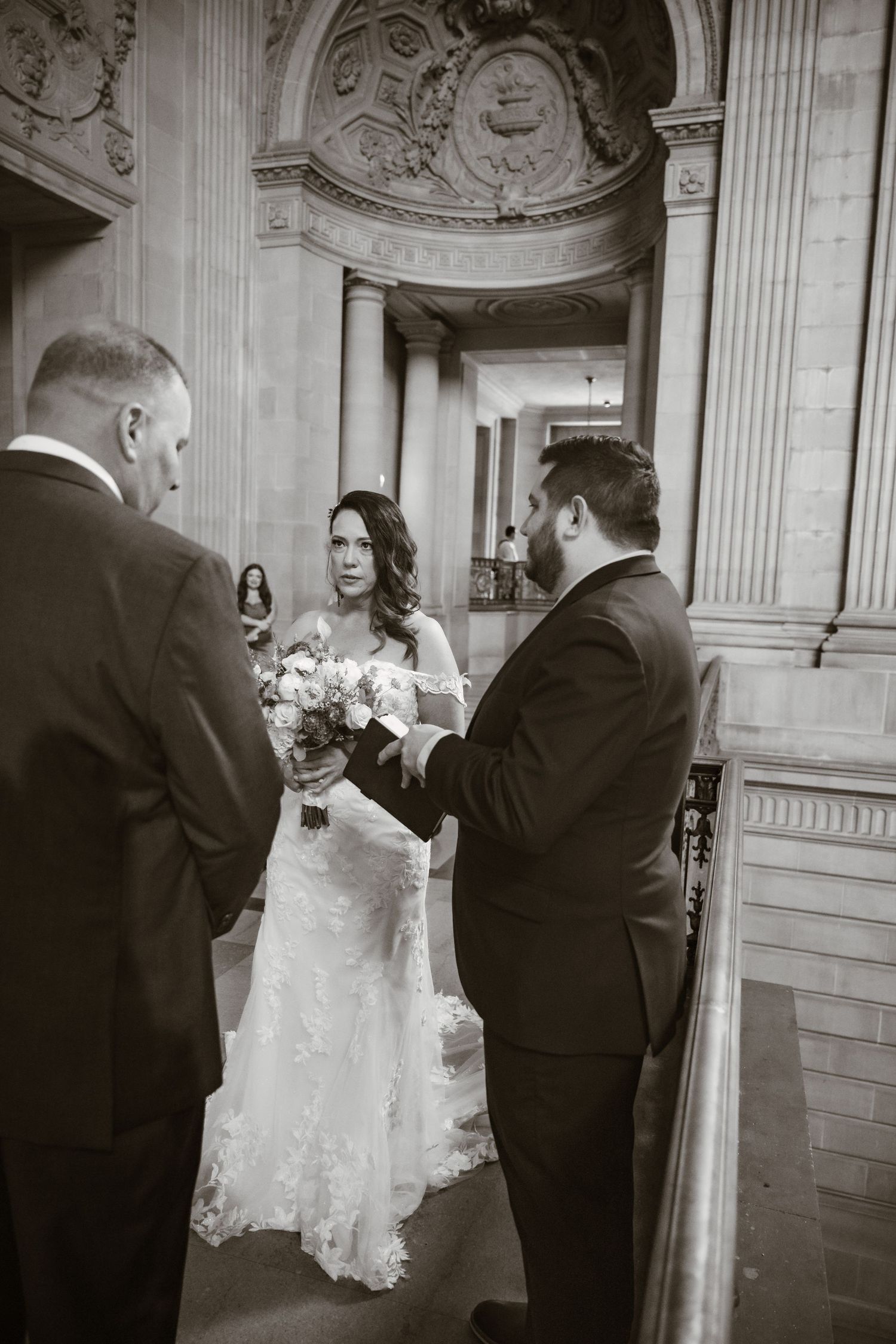 Wedding couple sharing intimate moment in elegant church hallway with classical architecture.