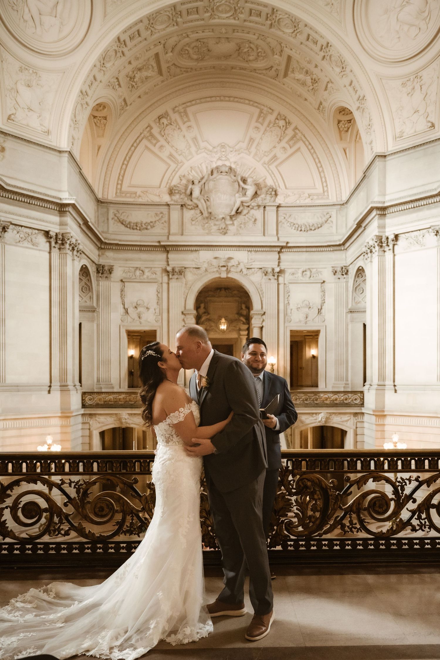 Elegant wedding ceremony in historic building with ornate white architectural details and balcony.