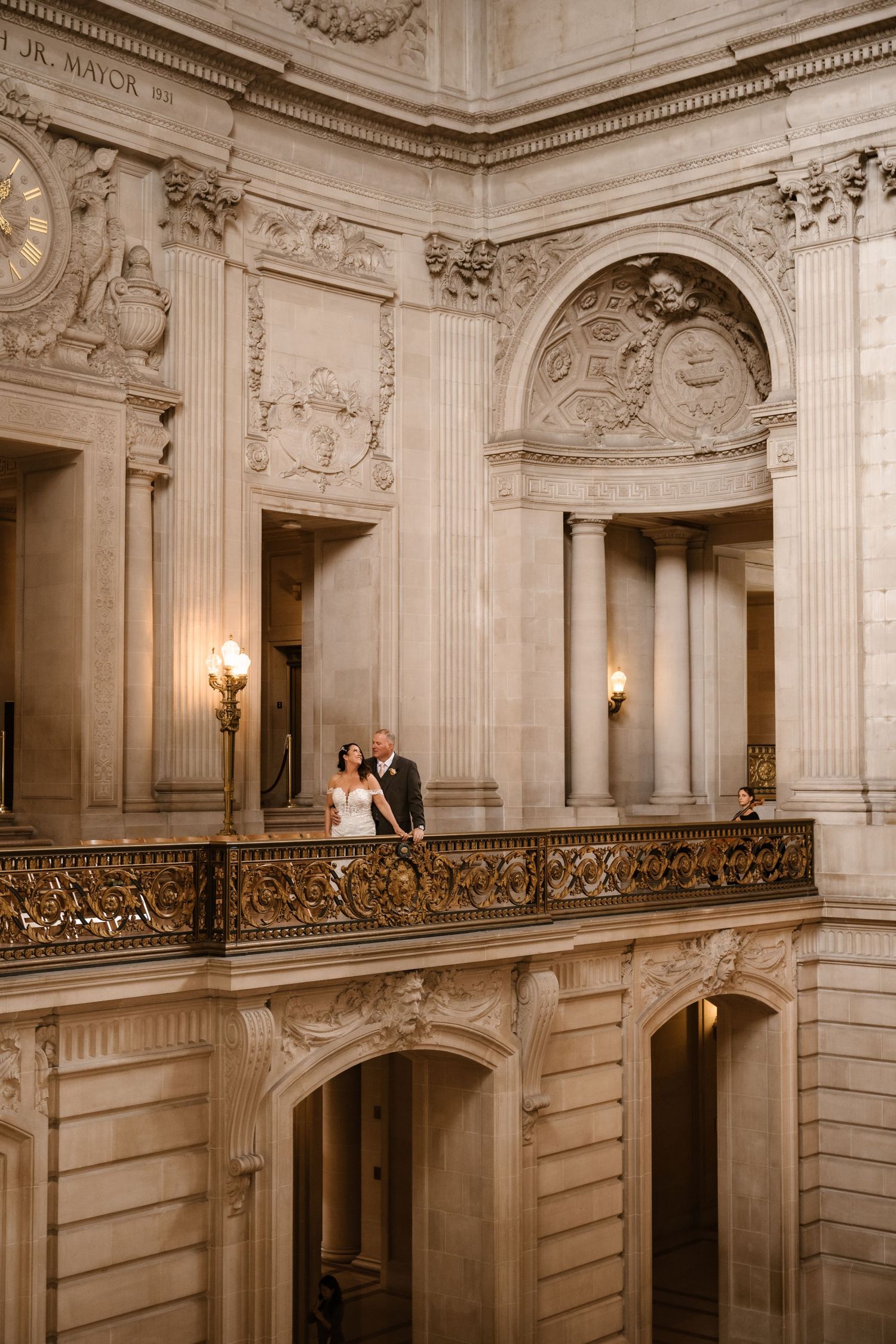 Romantic moment captured on grand balcony of historic building with ornate details.