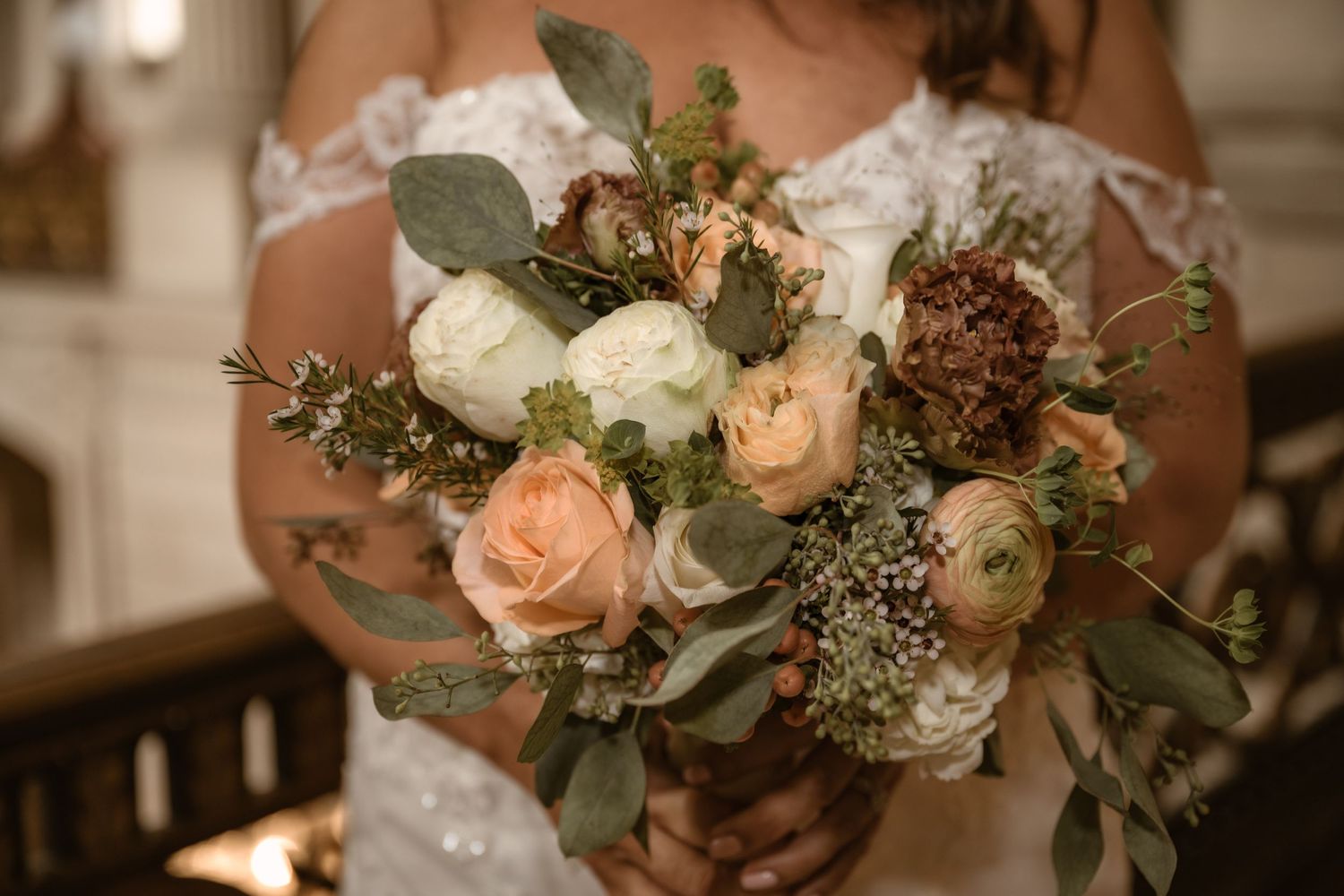 Close-up of romantic wedding bouquet featuring peach roses, white flowers and eucalyptus.
