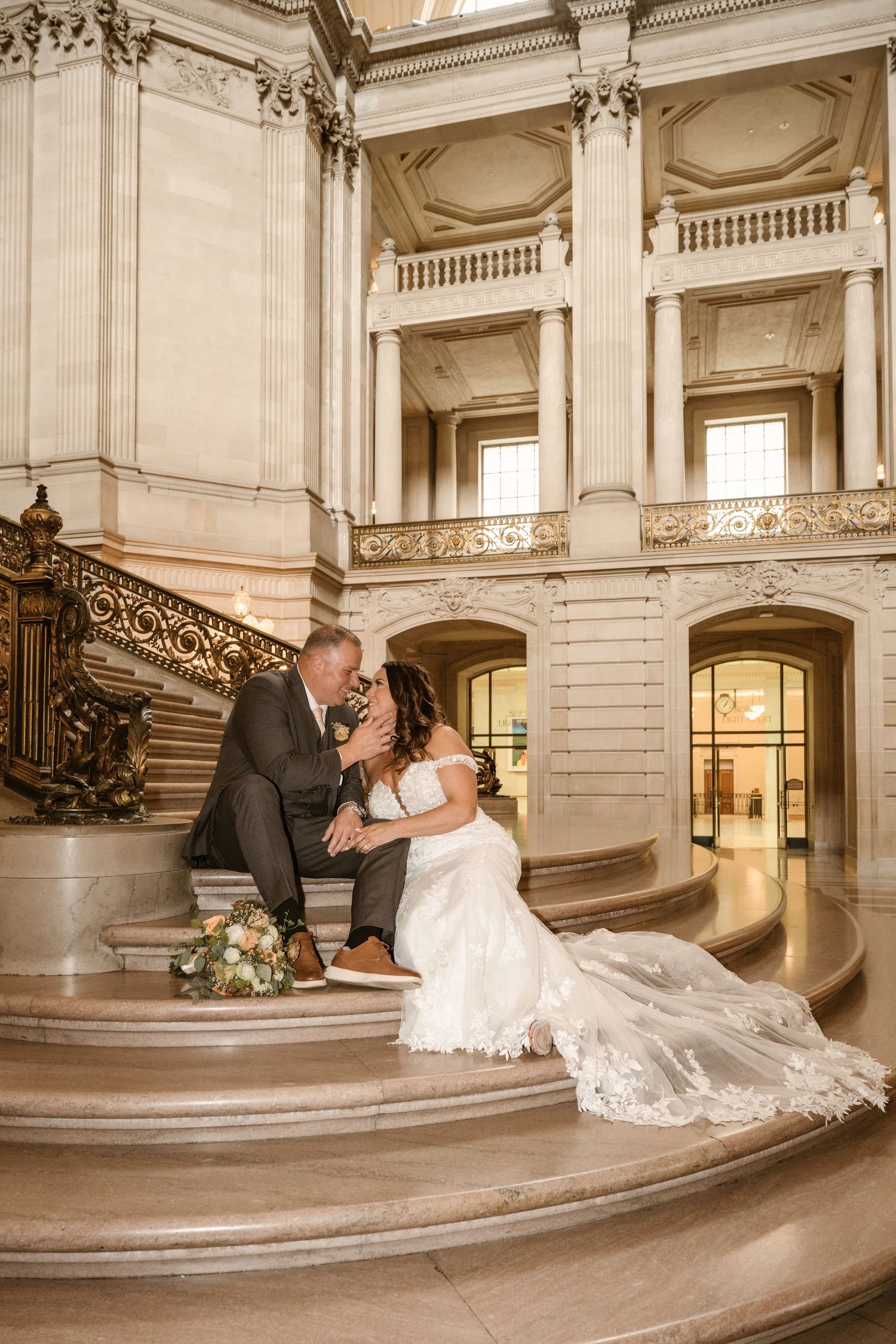 Series of romantic wedding poses on curved marble staircase in classical building.