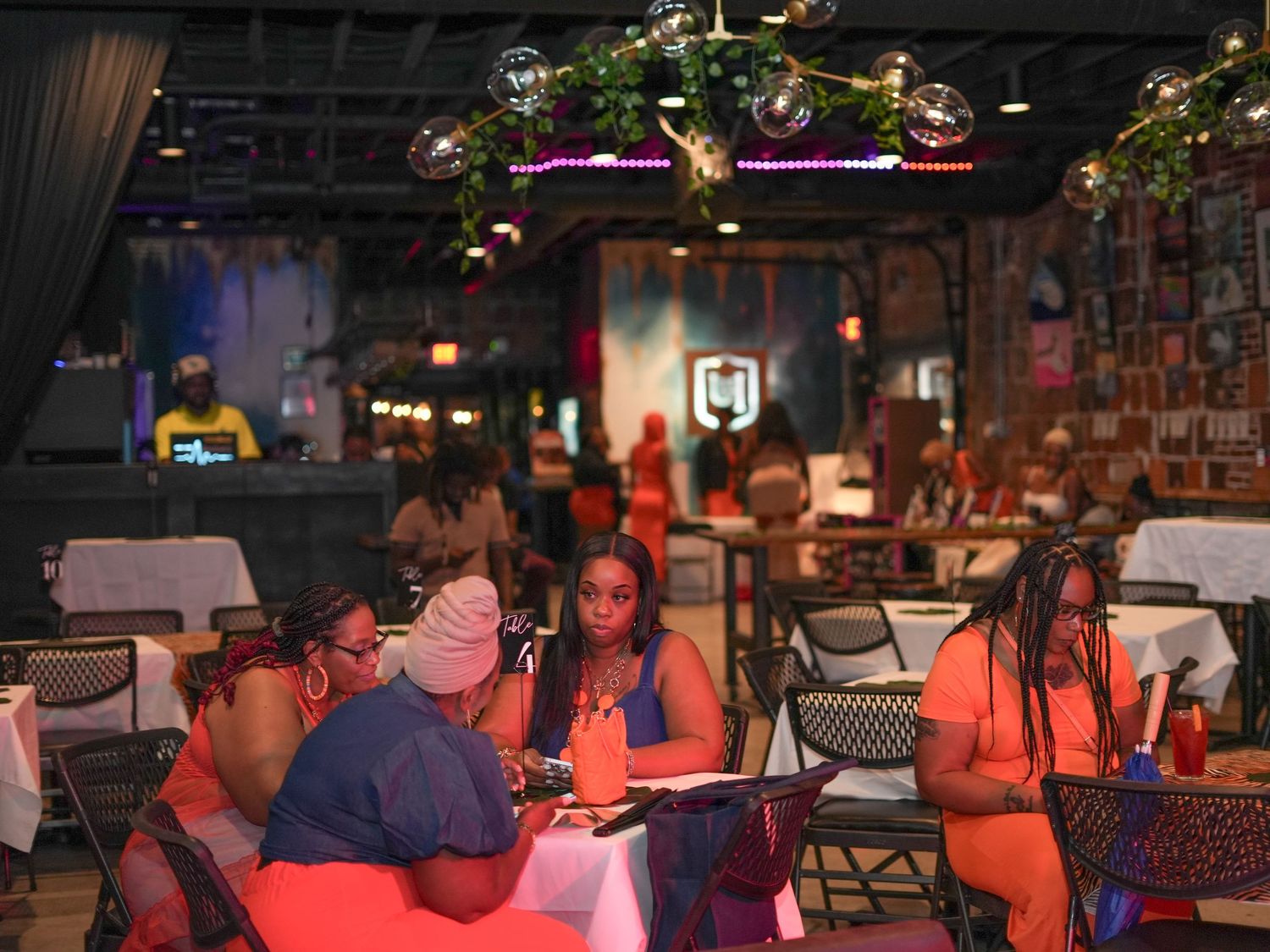 A dimly lit restaurant interior with patrons seated at tables under decorative hanging lights.