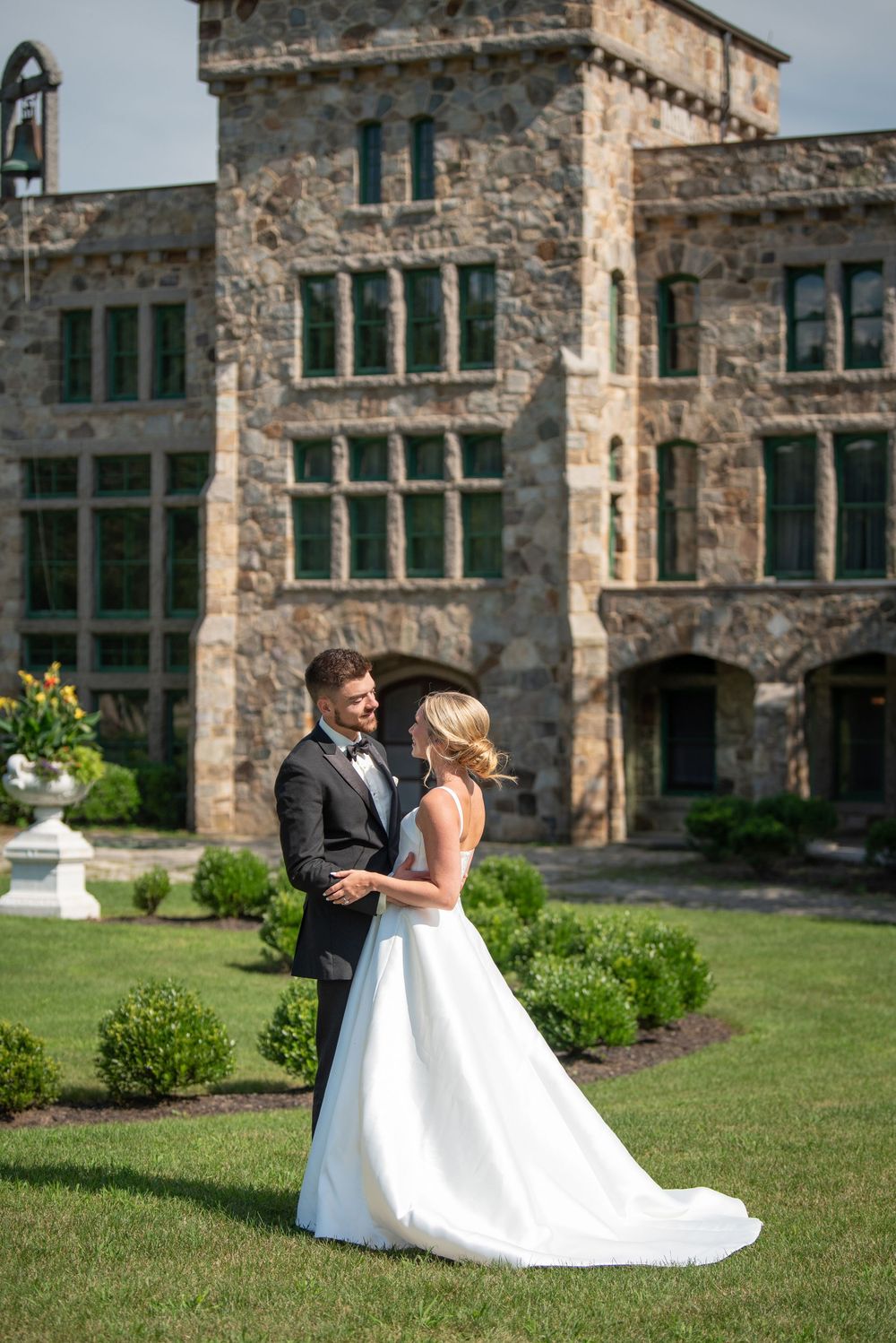 Wedding couple shares romantic moments on the lawn of a historic stone building.