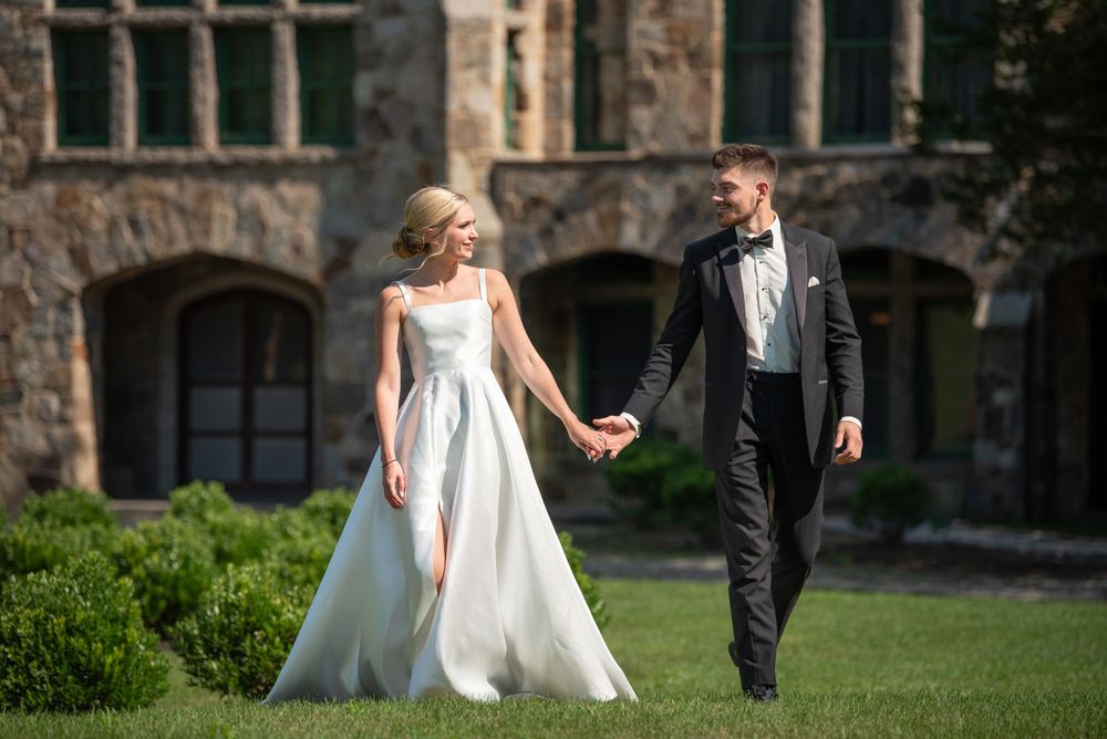 Elegant couple performs wedding dance moves on lawn of historic venue.