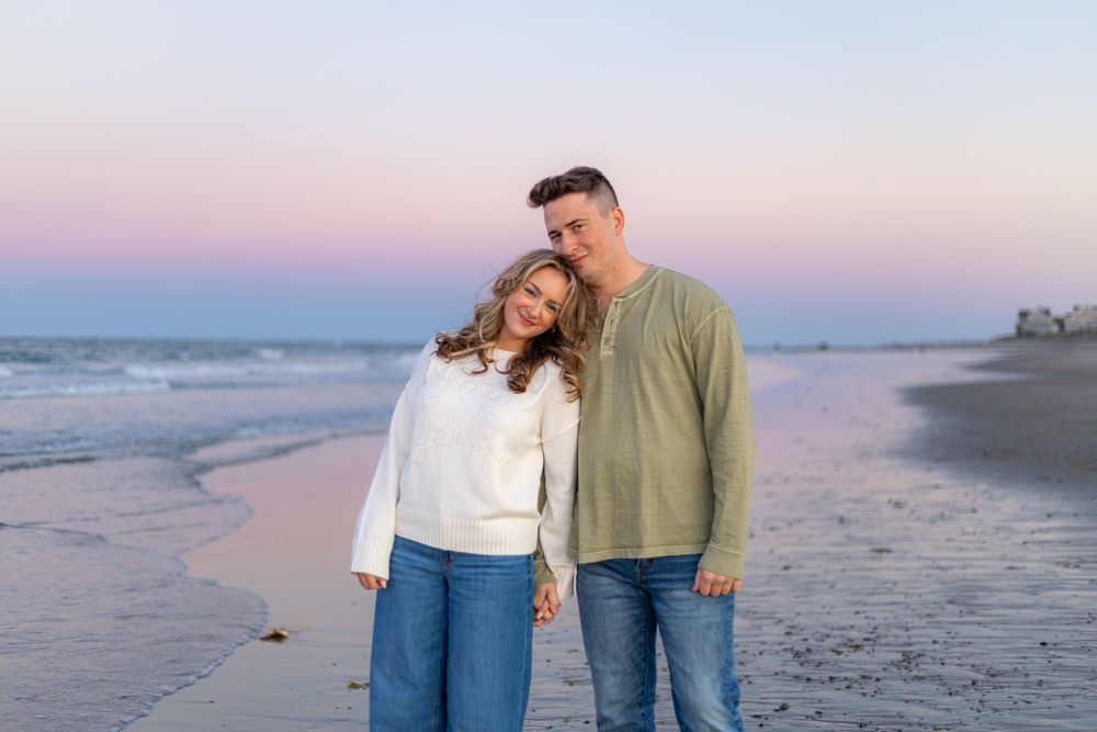 Couple walking along a peaceful beach at sunset during golden hour, creating romantic silhouettes against the ocean.