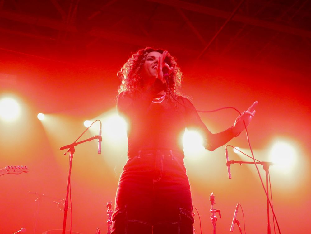 Dramatic silhouette of performer backlit by warm red stage lights during live show.