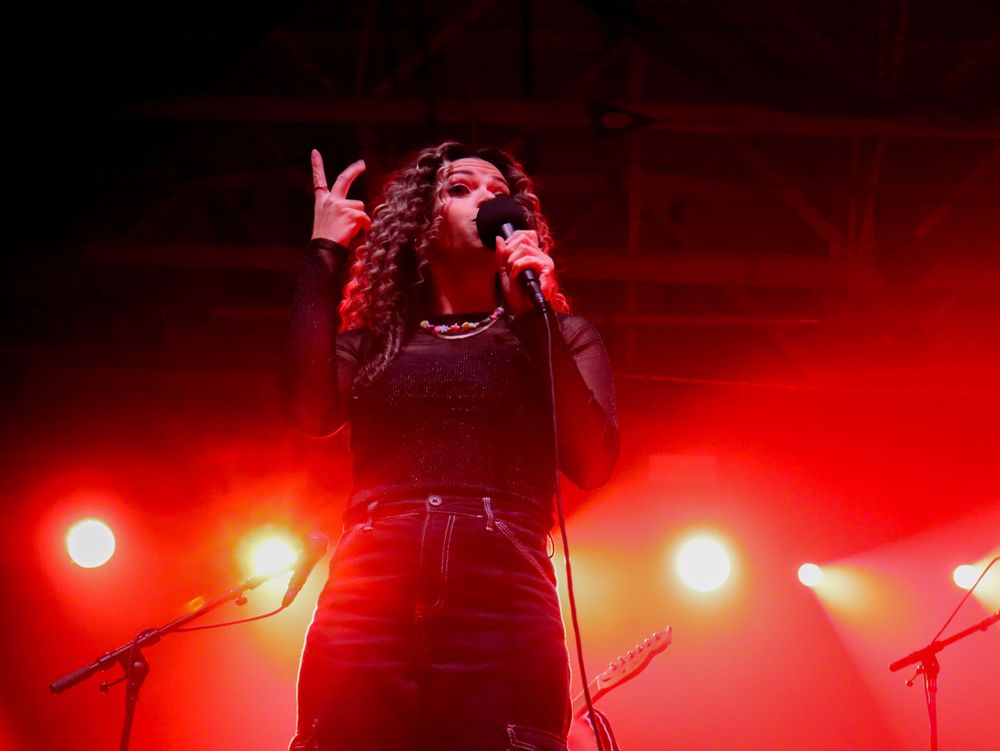 Concert performer silhouetted against intense red stage lighting during an energetic musical performance.