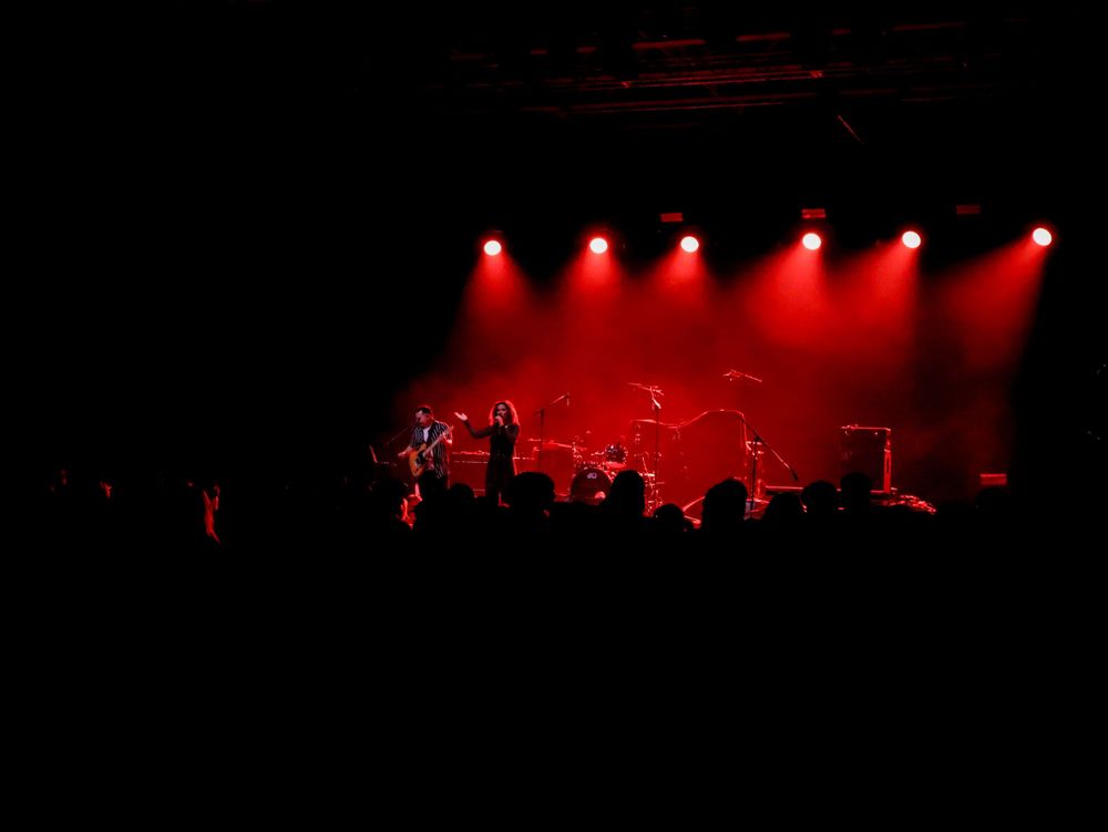 Concert stage illuminated by multiple red spotlights creating a dramatic atmosphere for live performance.