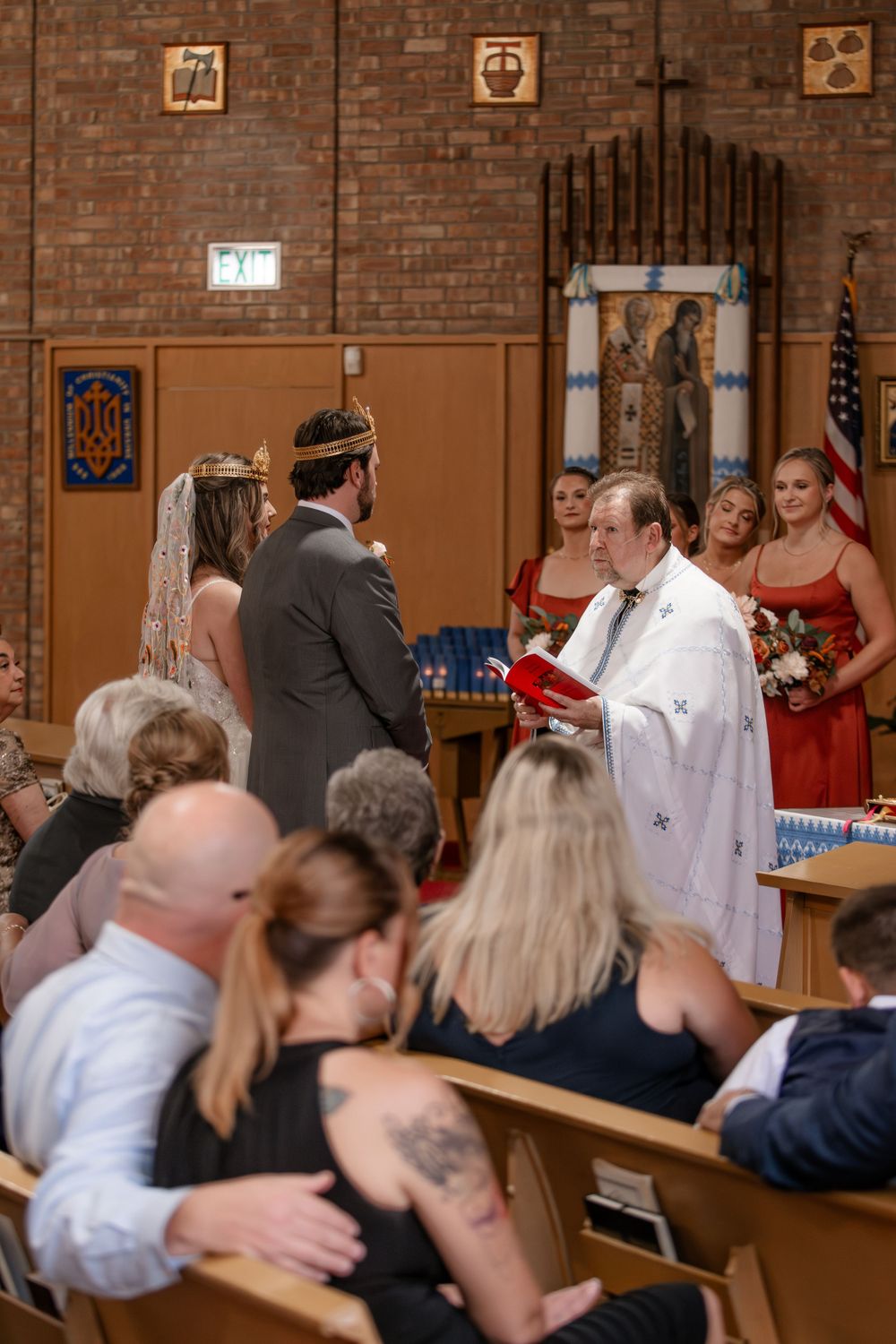 Bride and groom standing at altar during Ukrainian Orthodox wedding ceremony with guests seated.