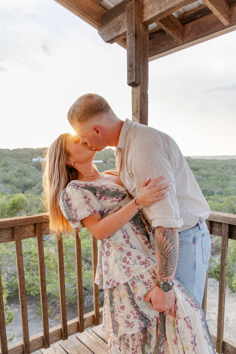 Sydney and Adan smiling and hugging after proposal at candlelit arch in Dripping Springs.