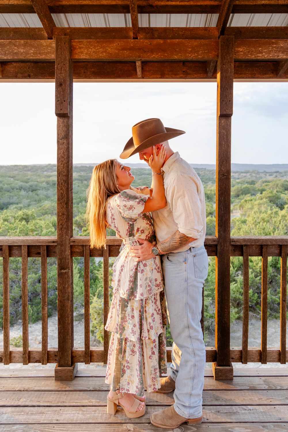 Couple sharing a kiss after engagement at rustic arch in Dripping Springs, Texas Hill Country.