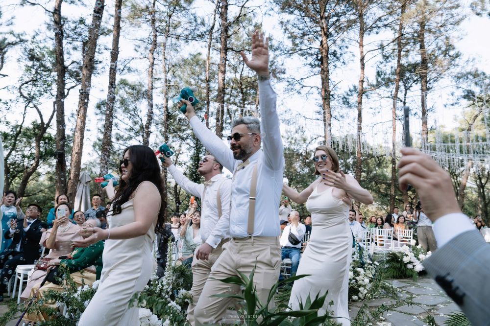 Groom and wedding party dance energetically down the aisle at an outdoor forest wedding ceremony.