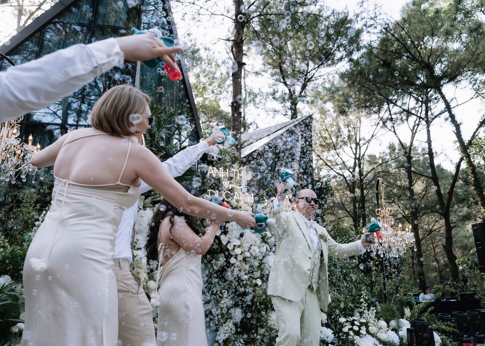 Bridesmaids and groom celebrating with confetti poppers at an elegant outdoor wedding ceremony.