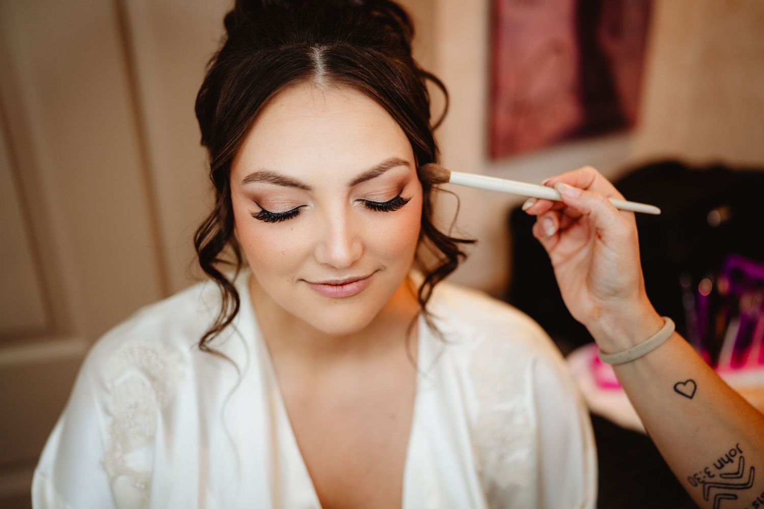 Bride getting ready with professional makeup being applied in a series of preparation photos shot in warm tones.