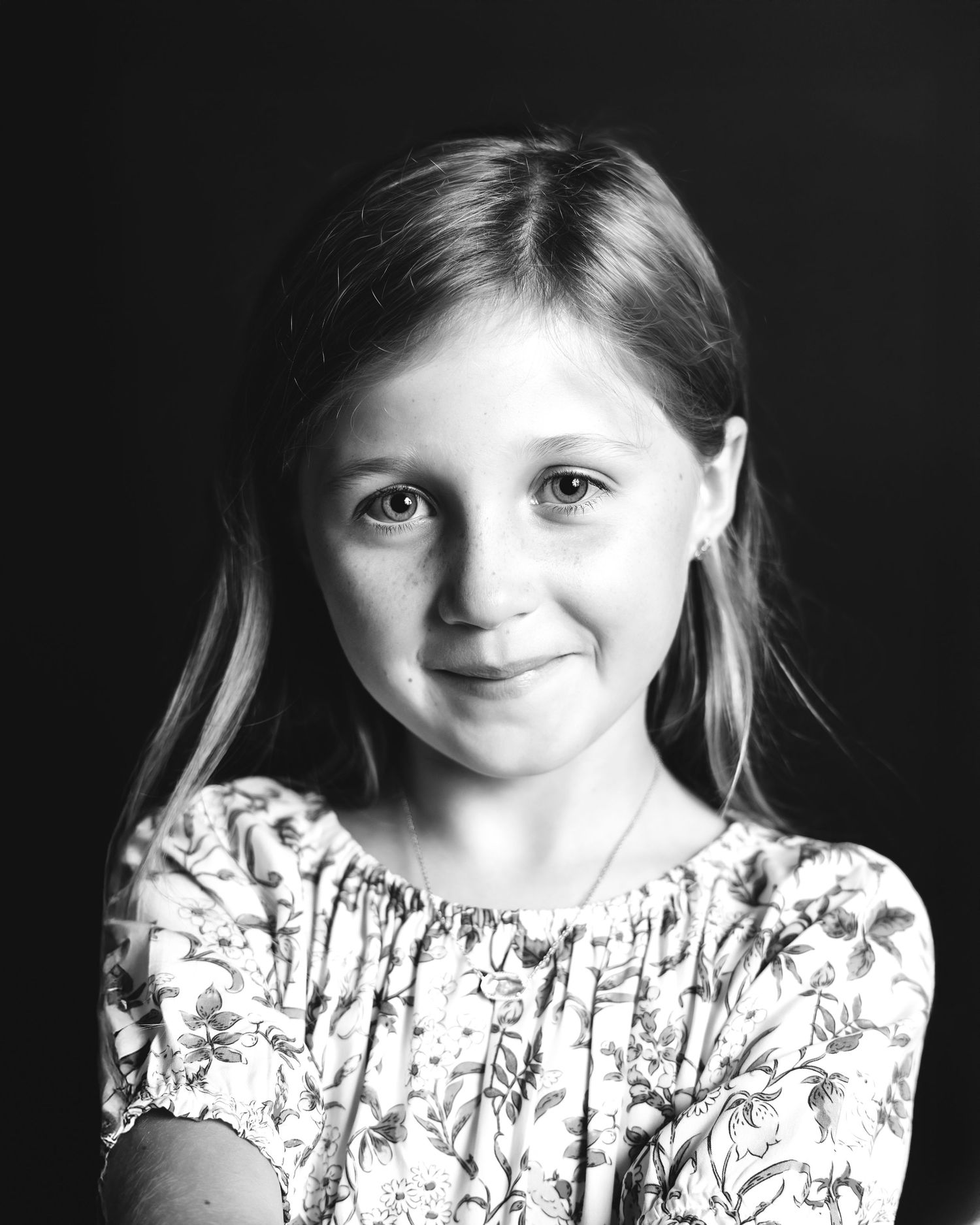 Black and white portrait series showing a young child in a floral dress with natural expressions.